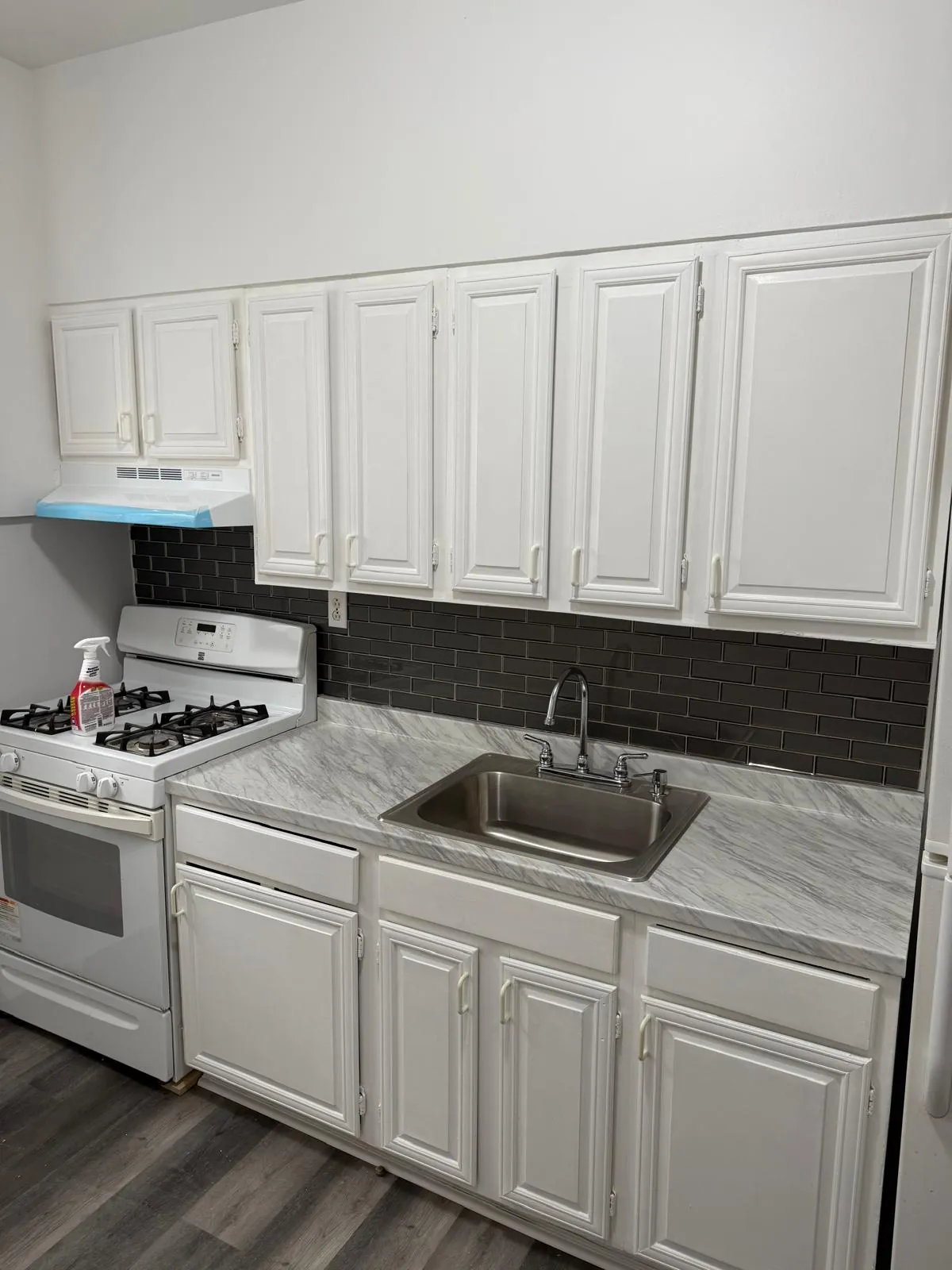 Kitchen remodel in Astoria, Queens: white cabinets, marble-look counter and dark tile backsplash