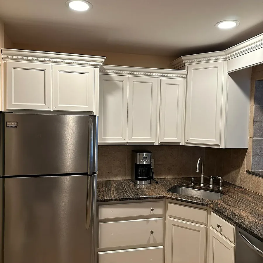 Kitchen remodel in Bellmore, NY: cabinets painted white under dentil crown molding, with dark granite counters