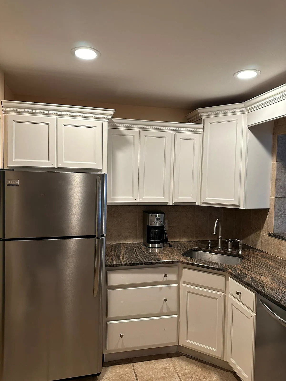 Kitchen remodel in Bellmore, NY: cabinets painted white under dentil crown molding, with dark granite counters