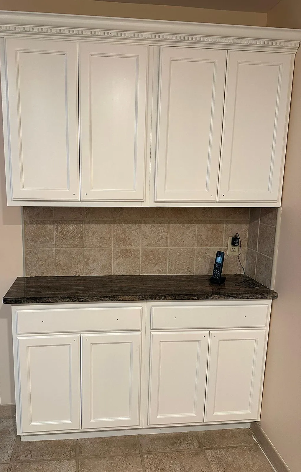 Kitchen remodel in Bellmore, NY: built-in cabinets painted white, with crown molding and a dark granite top