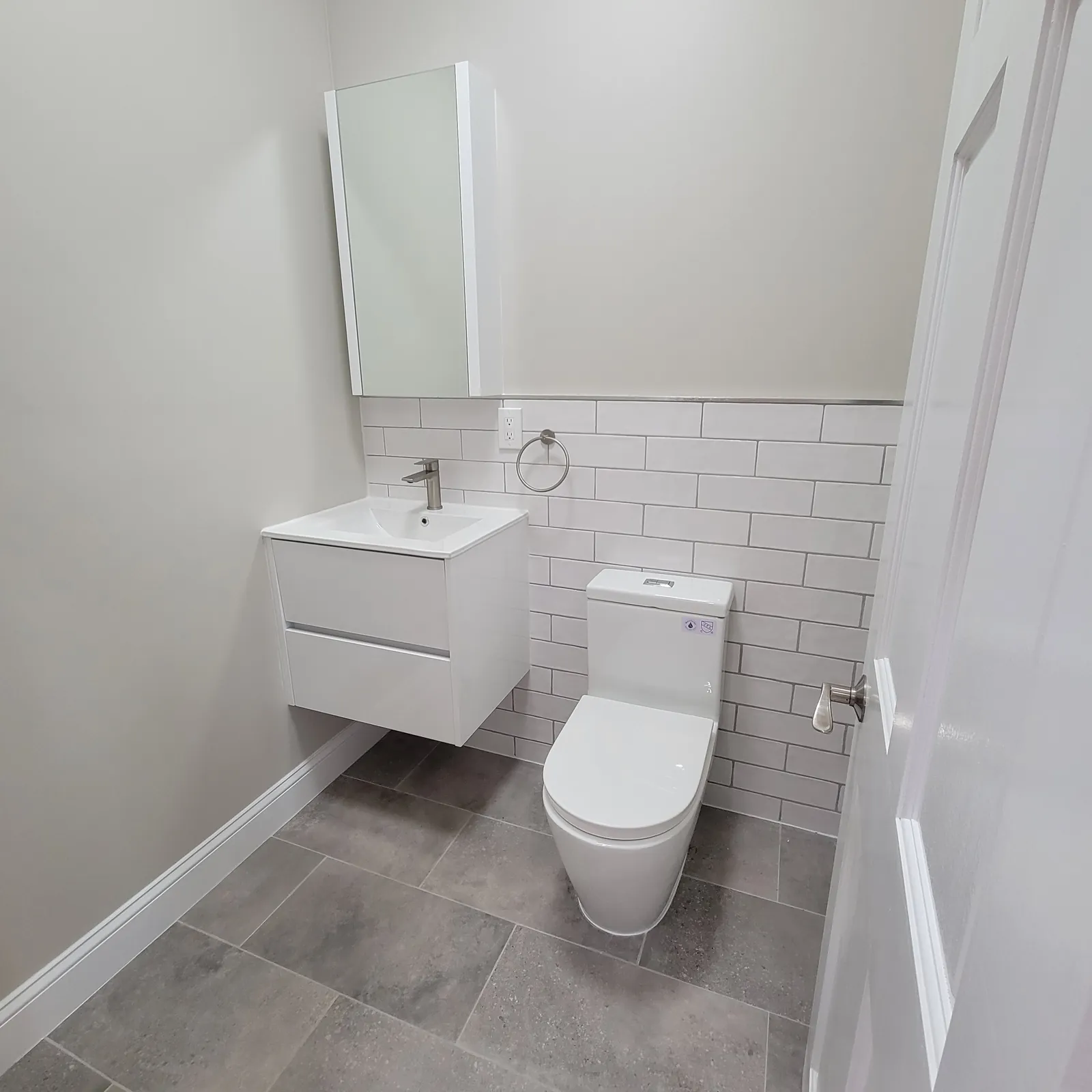 Bathroom remodel in the Bronx, NY: white floating vanity, subway tile and gray tile floor