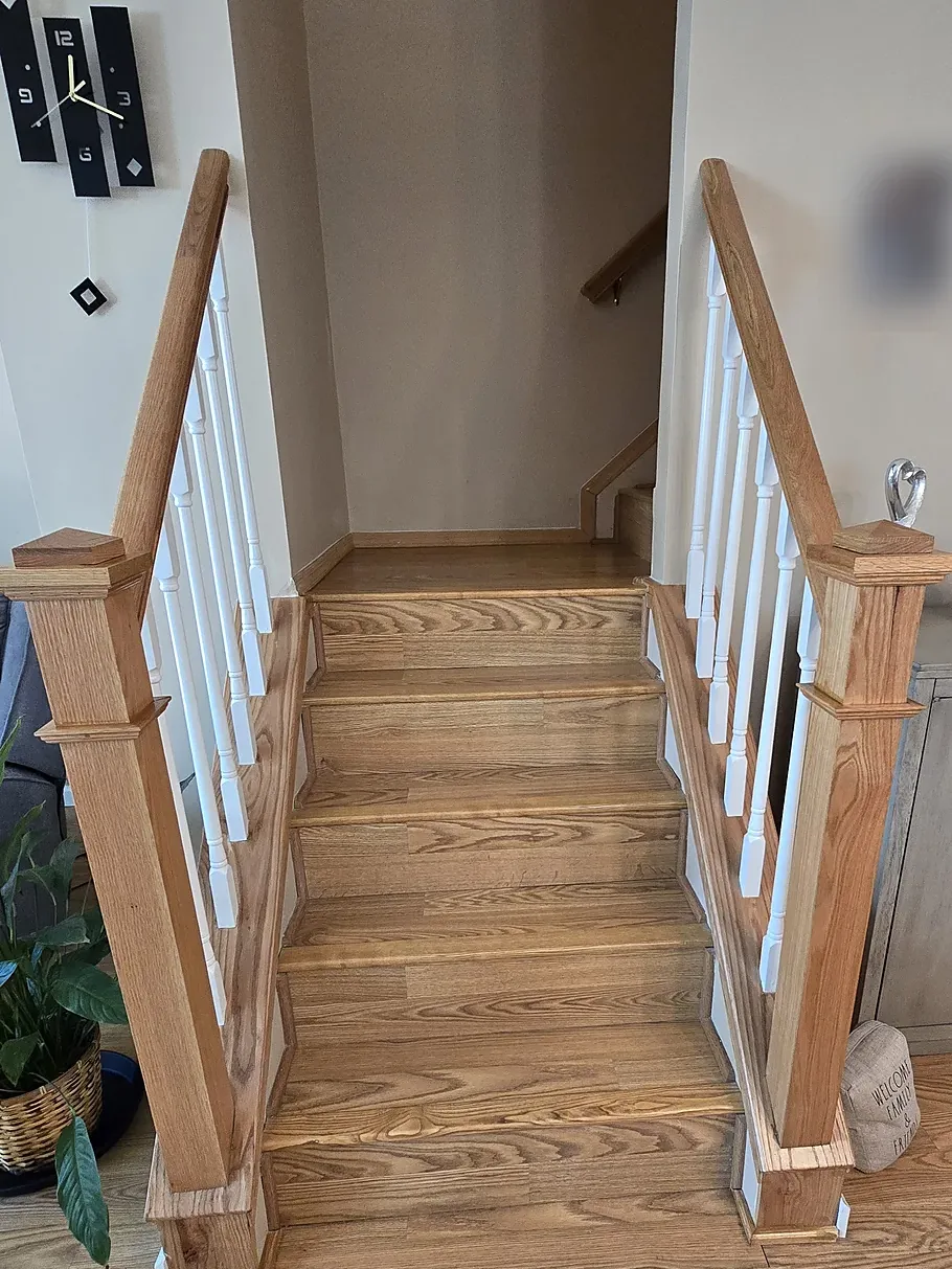 Staircase remodel in East Meadow, NY: a short flight of wood stairs between two new wood handrails with square newel posts and white spindles