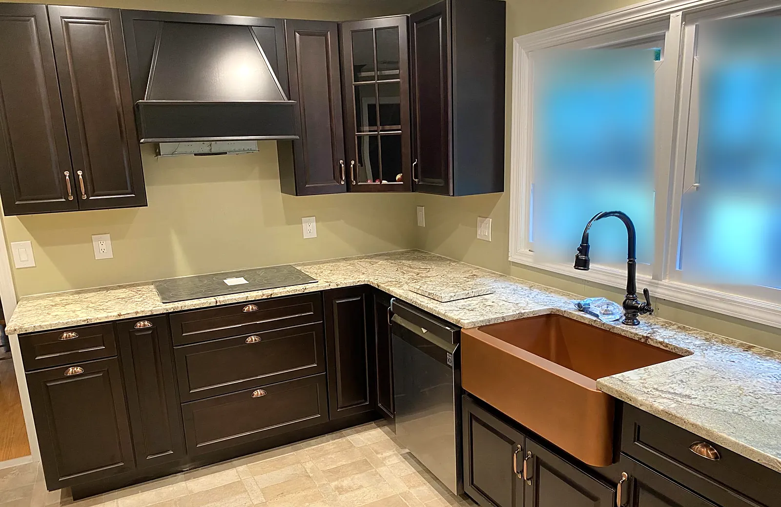 Kitchen remodel in East Moriches, NY: dark espresso cabinets, light granite counters, a black hood and a copper farmhouse sink