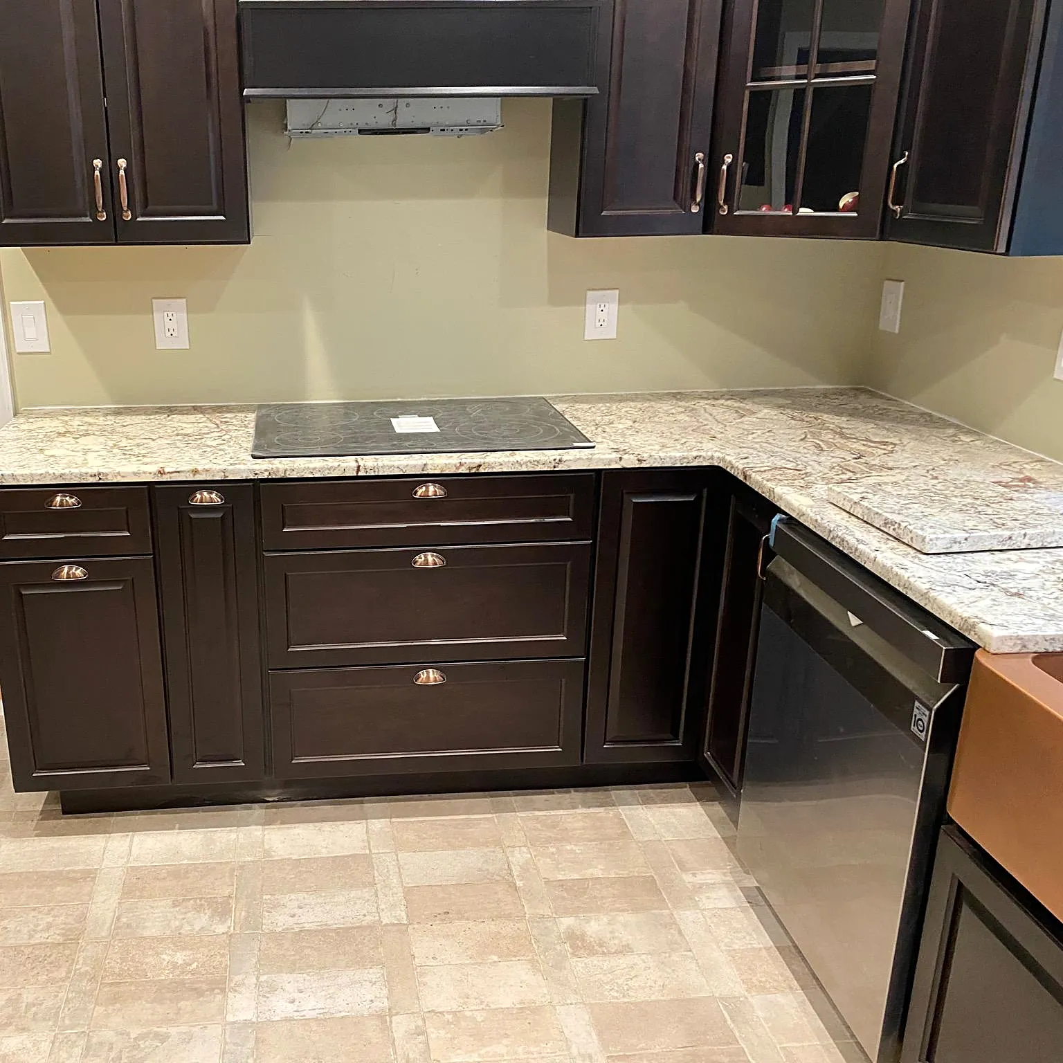 Kitchen remodel in East Moriches, NY: dark espresso cabinets with copper cup pulls, light granite counters and a cooktop
