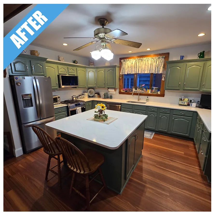 Kitchen remodel in Floral Park, NY: sage green cabinets, a white-topped island and a wood floor