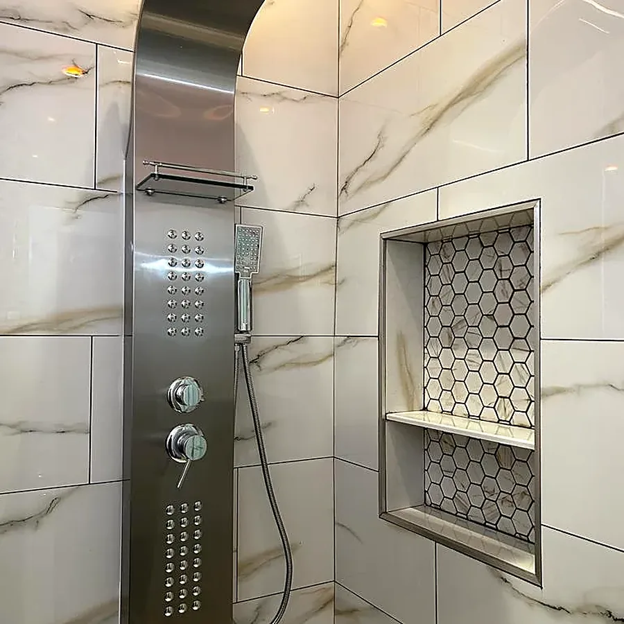 Shower remodel in Flushing, Queens, NY: a stainless shower panel and a hexagon mosaic niche in white and gold marble-look tile