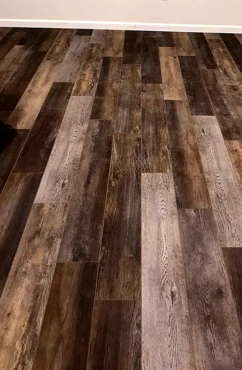 Basement remodel in Franklin Square, NY: a gray and brown wood-look vinyl plank floor in a finished basement with white baseboards