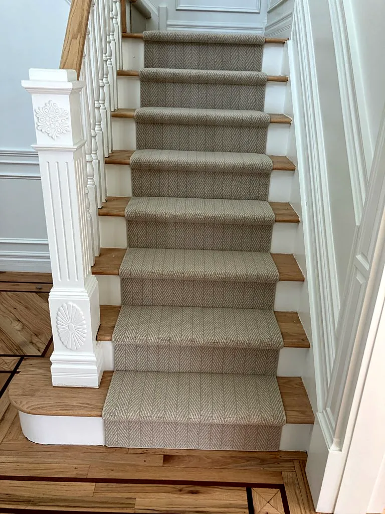 Staircase remodel in Huntington, NY: a herringbone-weave stair runner on natural wood treads with white risers and a carved white newel post