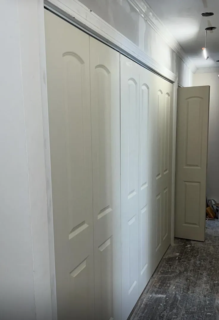 Hallway remodel in Long Beach, NY: new white panel closet doors, before the floor was finished