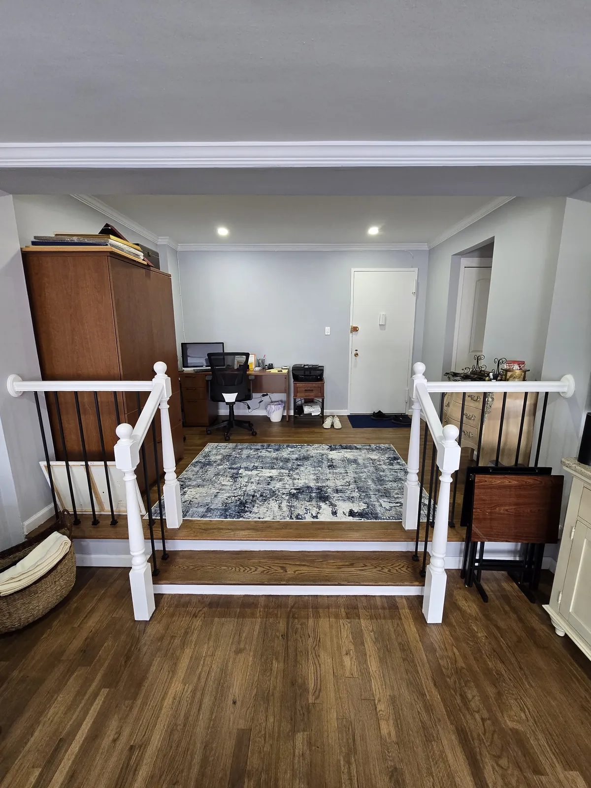 Living area remodel in Long Beach, NY: wood floor and a white railing with black spindles at the step