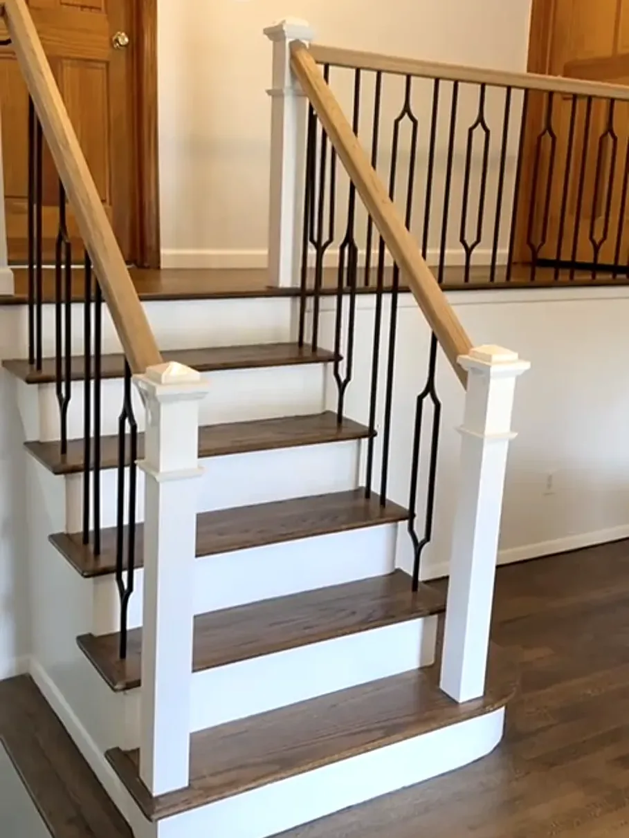 Split-level staircase remodel in Massapequa Park, NY: stained treads with white risers, white newel posts, wood rails and black diamond-pattern spindles