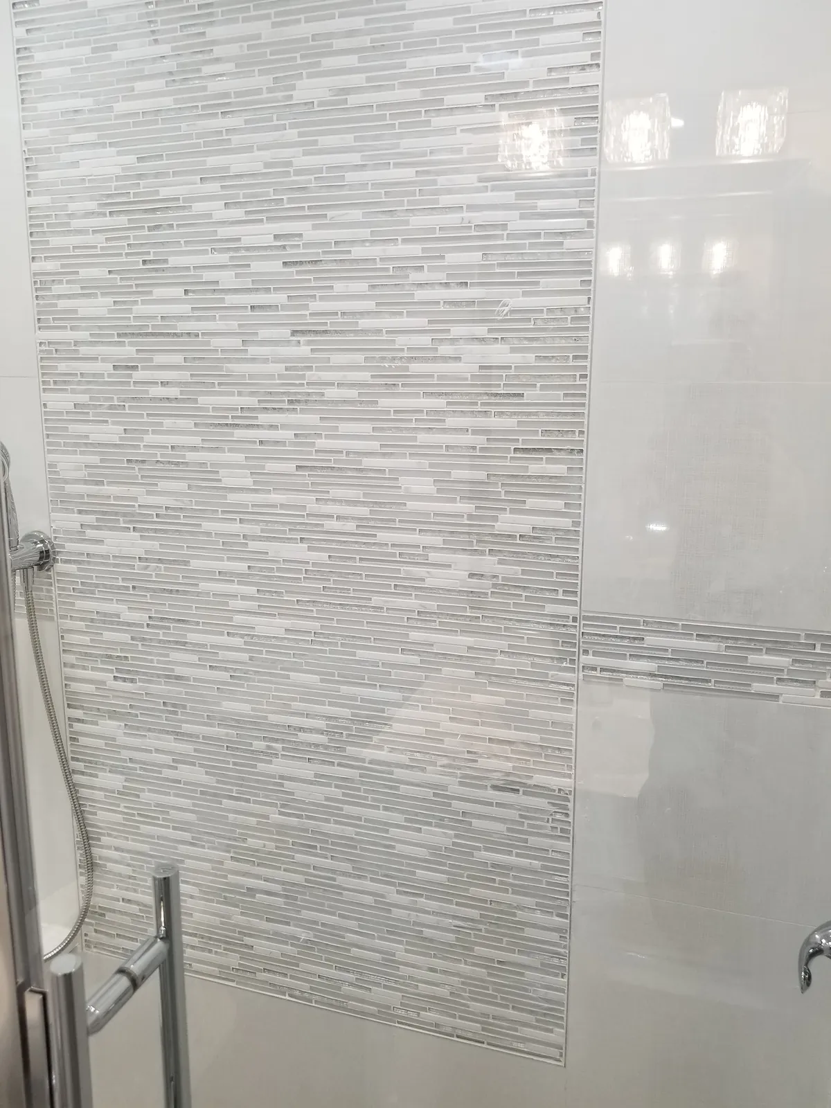 Bathroom remodel in Massapequa, NY: linear glass mosaic tile panel in a white-tiled shower