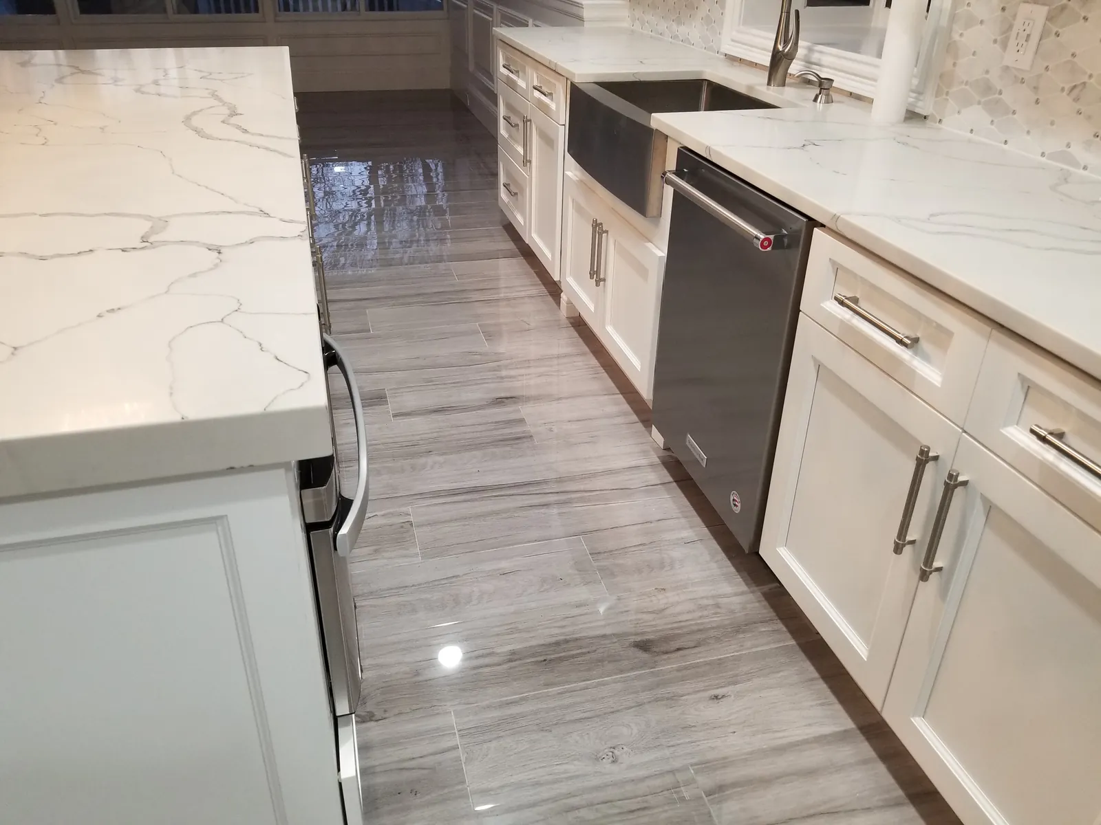 Kitchen remodel in Massapequa, NY: apron-front sink, white cabinets and gray plank-look floor