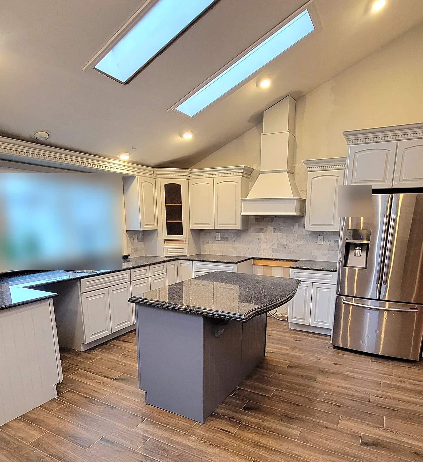 Kitchen remodel in Merrick, NY: cream cabinets with dentil crown molding, a white range hood, a gray island with black granite and two skylights