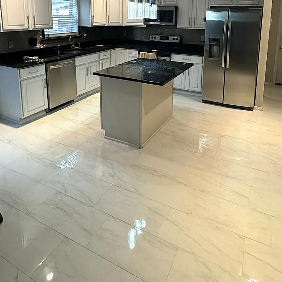 Kitchen remodel in Nesconset, NY: white cabinets, a black granite island with pendant lights and glossy marble-look floor tile