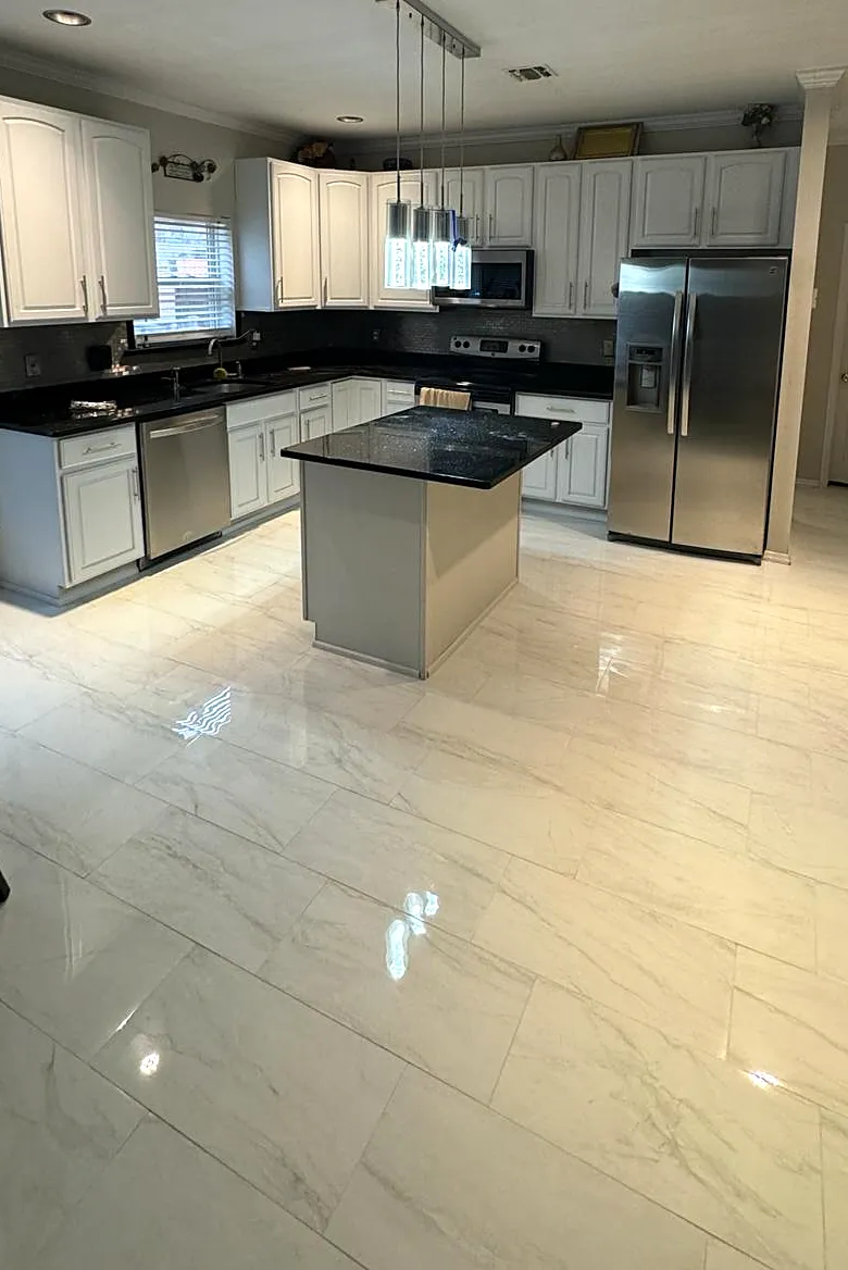 Kitchen remodel in Nesconset, NY: white cabinets, a black granite island with pendant lights and glossy marble-look floor tile