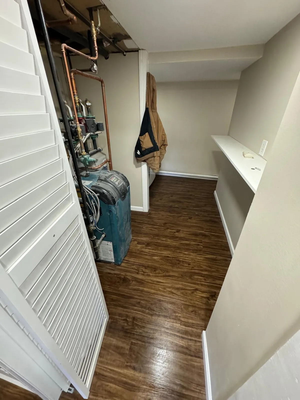 Basement remodel in New Hyde Park, NY: dark plank floor in the utility area beside the boiler