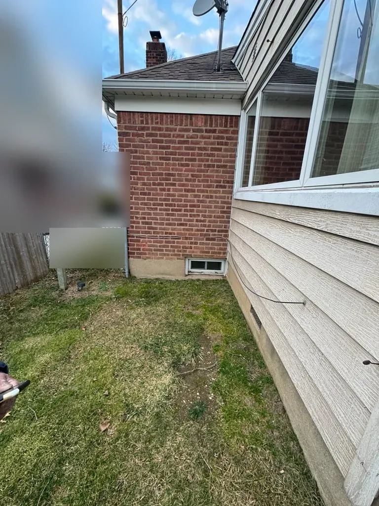 Side of a brick house with siding and a small lawn, at a New Hyde Park, NY job