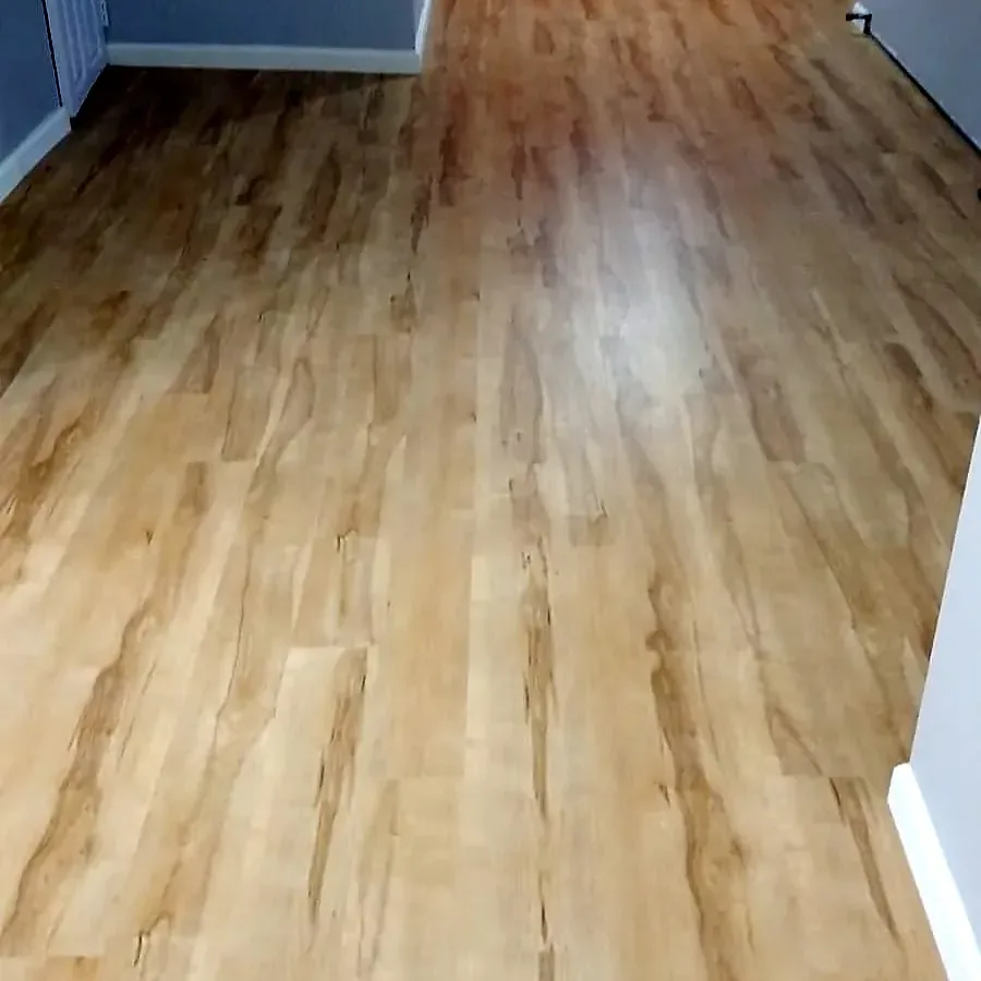 Basement remodel in Roosevelt, NY: a light wood-look vinyl plank floor running through a long basement room with an orange accent wall