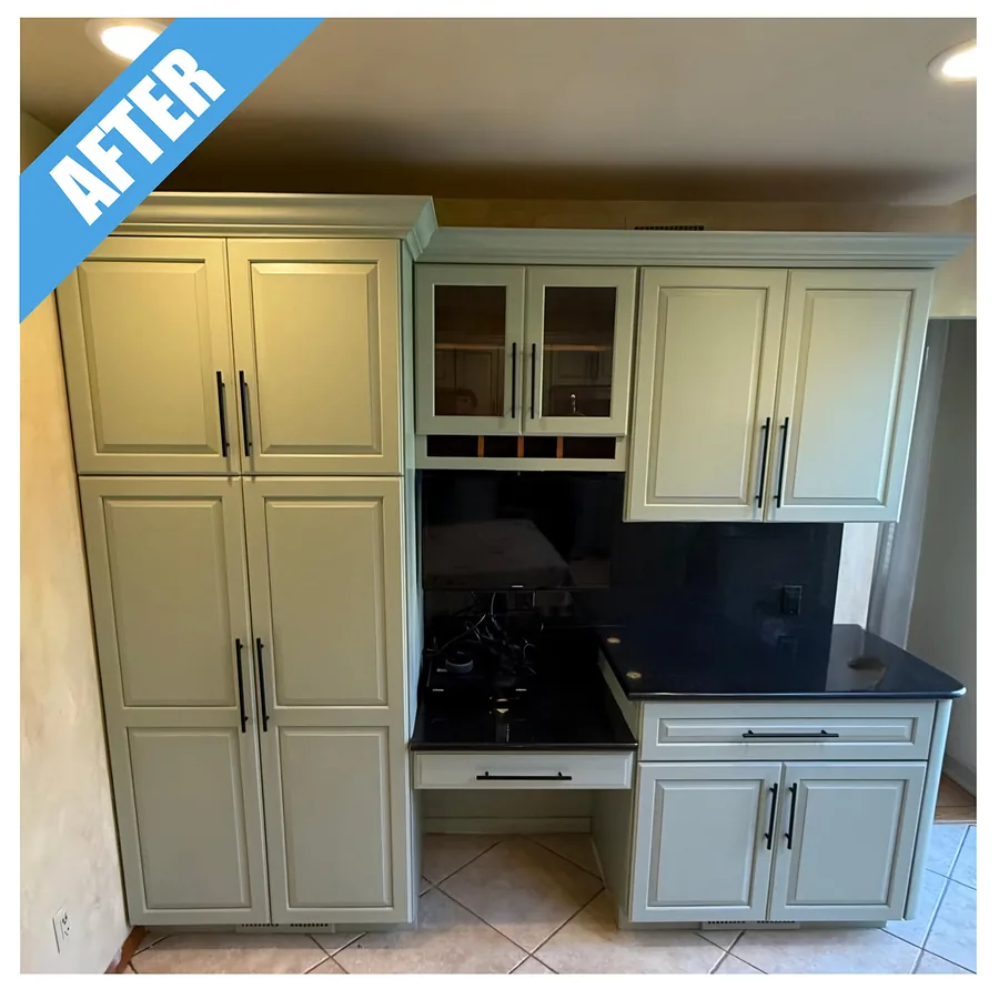 Kitchen remodel in Upper Brookville, NY: cabinets painted a soft green, with dark counters and glass-front upper cabinets