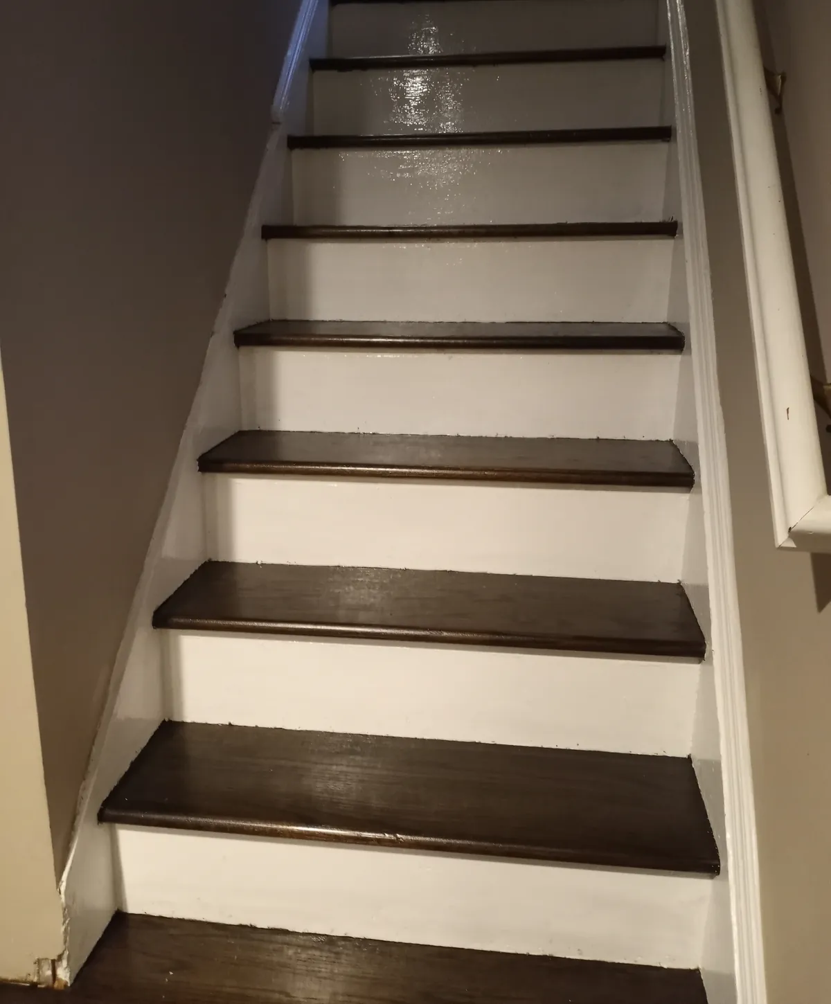 Staircase remodel in Valley Stream, NY: dark stained oak treads and white risers running up a narrow flight beside a white handrail
