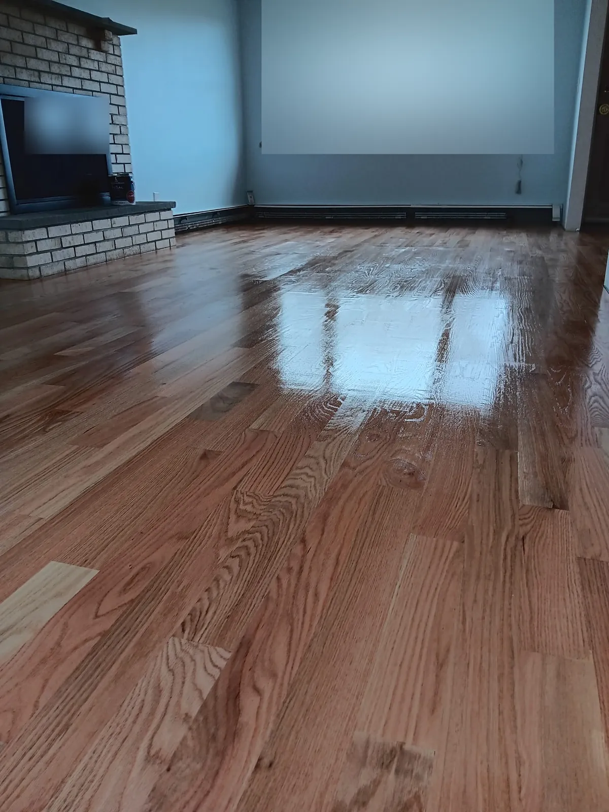 Living room remodel in Wantagh, NY: refinished wood floor and brick fireplace