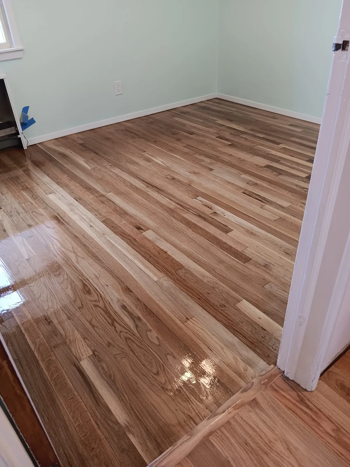 Room remodel in Wantagh, NY: freshly refinished wood floor in an empty room