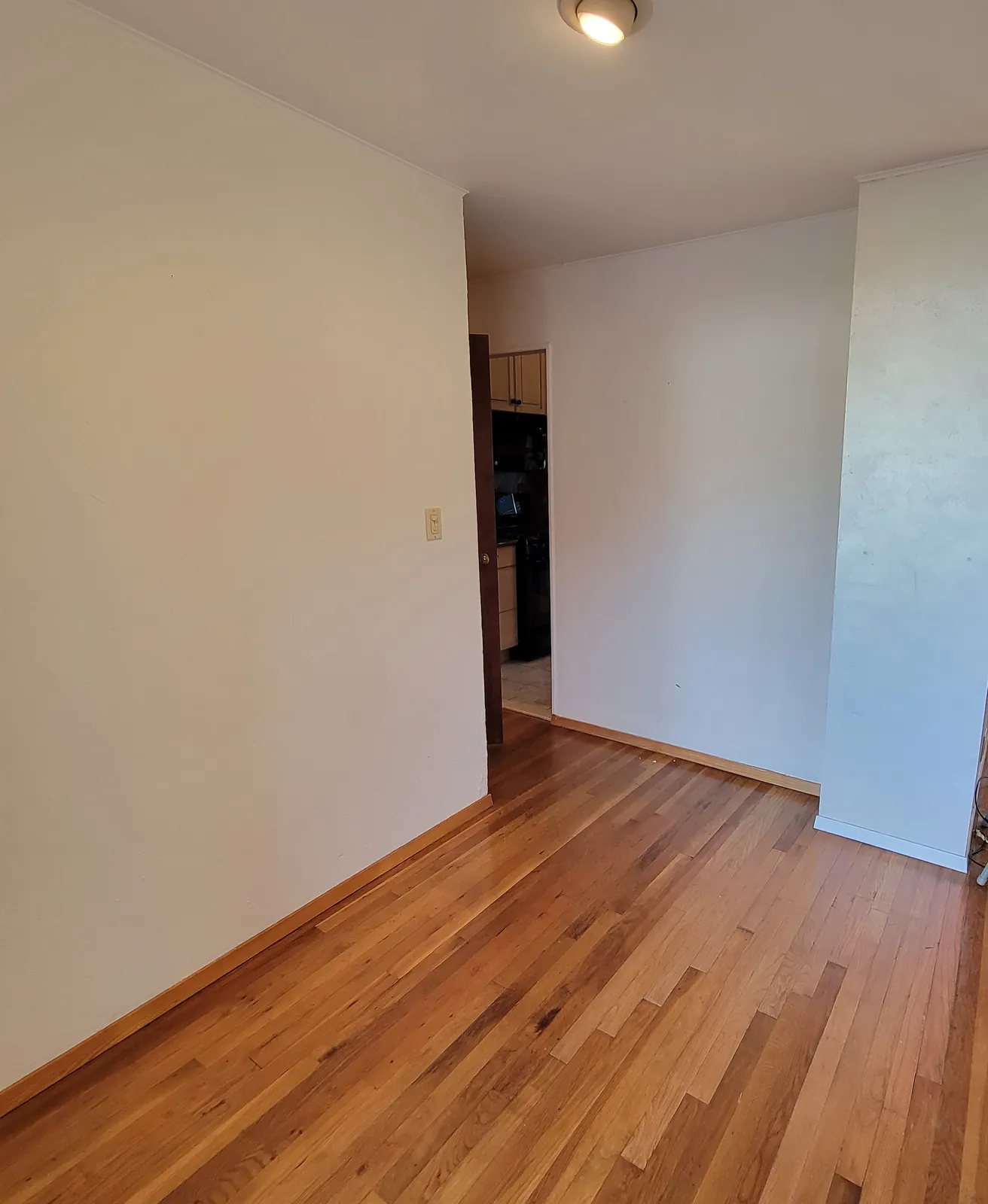 Room remodel in Wantagh, NY: refinished wood floor running to the kitchen doorway