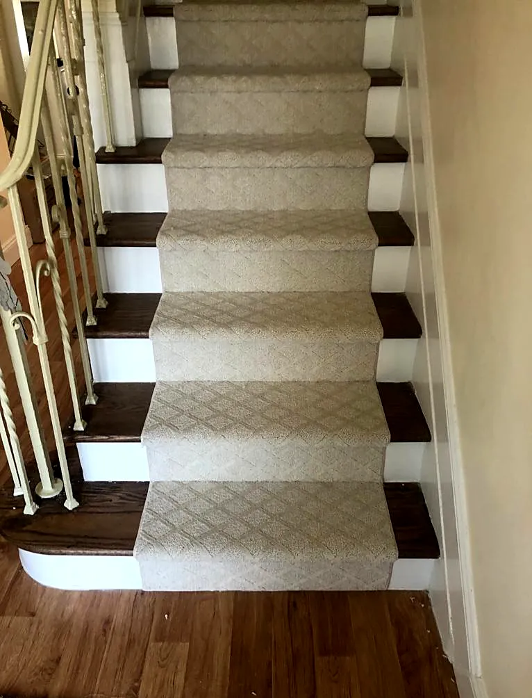 Staircase remodel in West Hempstead, NY: a cream patterned stair runner over dark wood treads and white risers above a wood floor